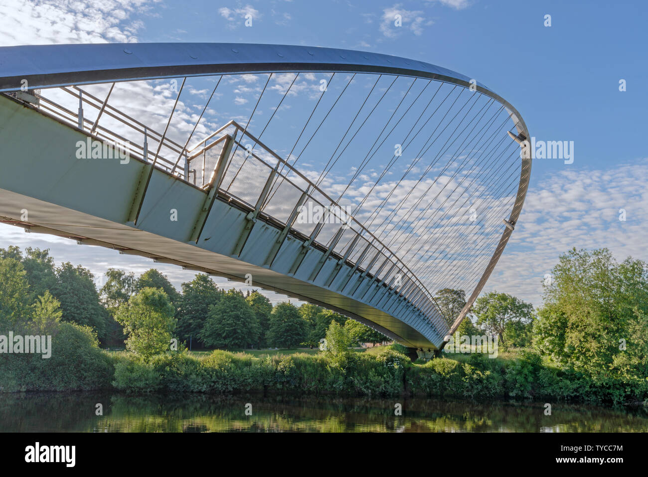 Il Millennium Bridge a York. Un moderno progettato in acciaio ponte di sospensione con un arco di curva e cavi. Un cielo blu con nuvole è sopra. Foto Stock