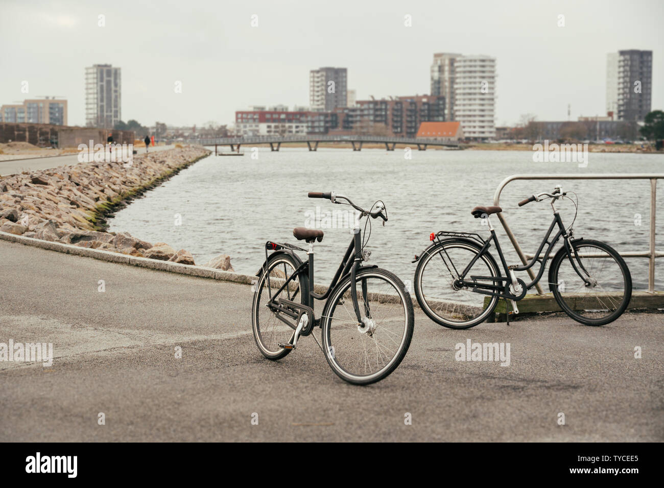 Due identici retrò città nero biciclette parcheggiate sul terrapieno, strada lungo il Mar Baltico, embankment con asfalto percorso di sfondo hdan e città Copenhag Foto Stock