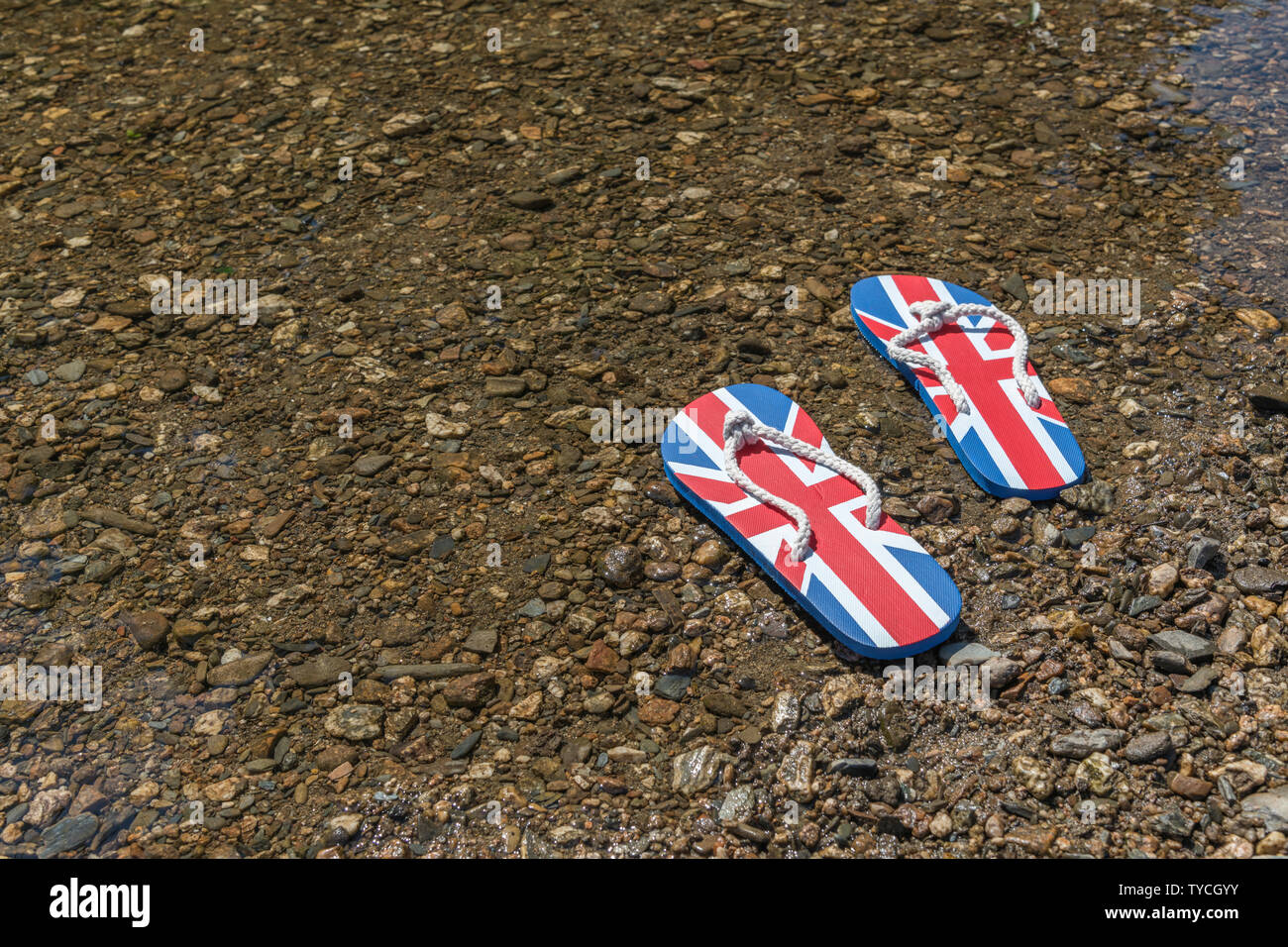 Union Jack flip-flop sul fiume Shingle. Metafora 2021 Regno Unito staycation, vacanze a casa, staycation Cornwall, country break, flip flop calzature. Foto Stock
