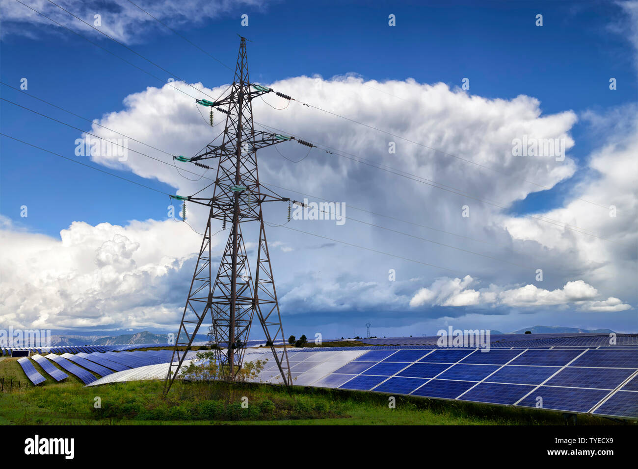 Uomo e natura energia. Campo con pannelli solari e linee elettriche ad alta tensione con grande tempesta sullo sfondo. Foto Stock