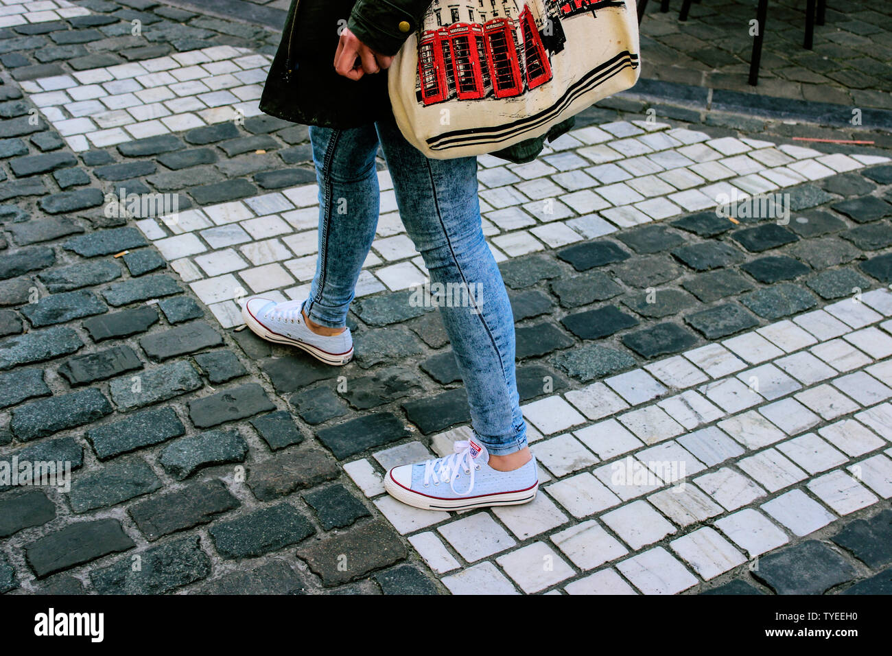 Moda Donna jeans blu e snickers sulla roccia cubi strada su una zebra crossing Foto Stock