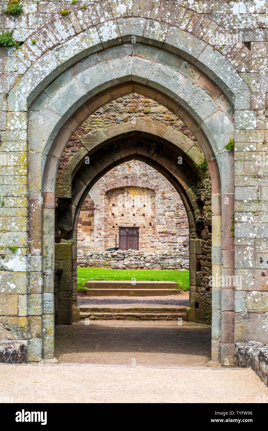 Una vista attraverso la porta sud archi nel Fountain Court e la cappella a Raglan Castle, Galles Foto Stock