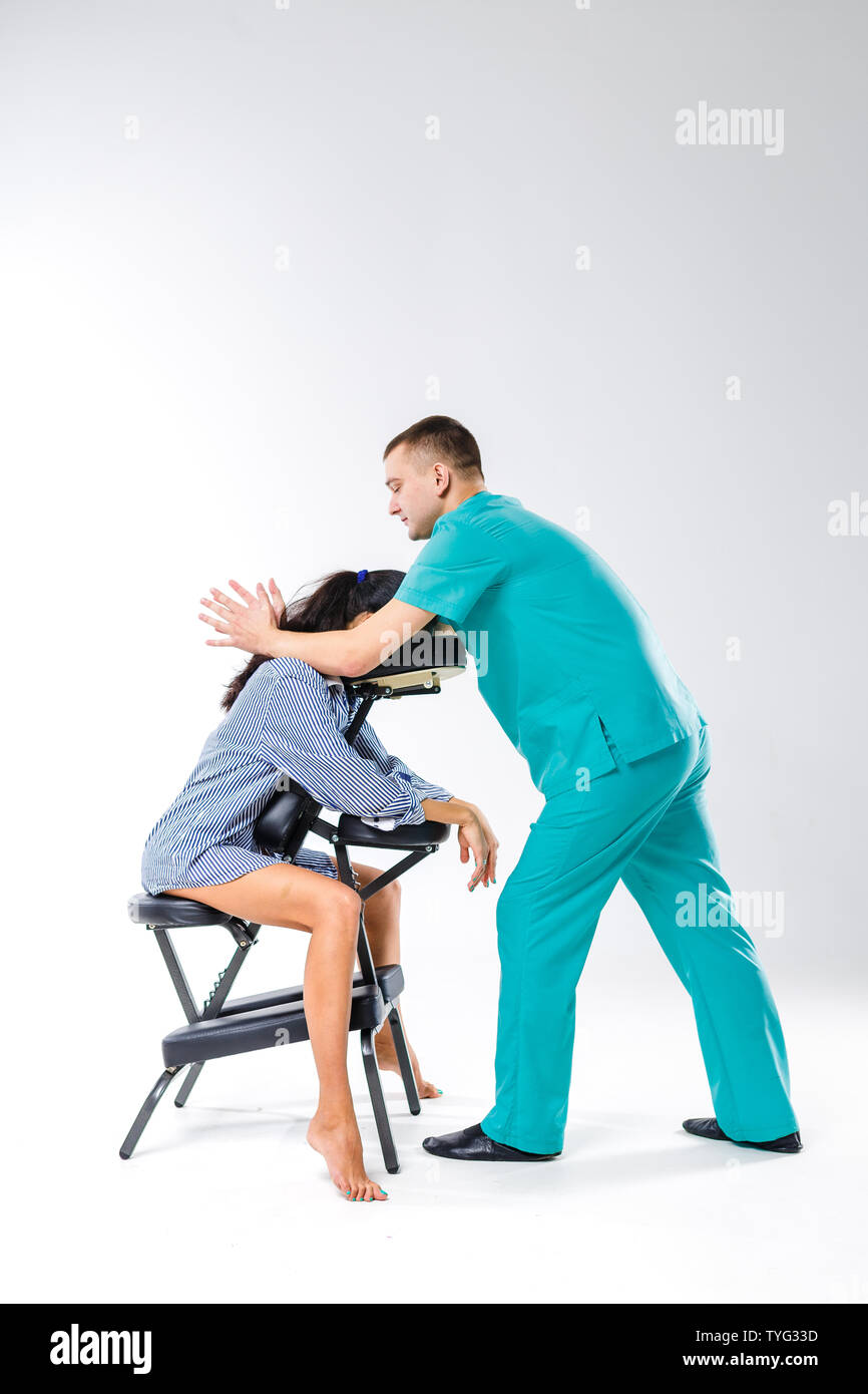 Massaggio a tema e ufficio. Terapista del sesso maschile con tuta blu  facendo massaggi schiena e