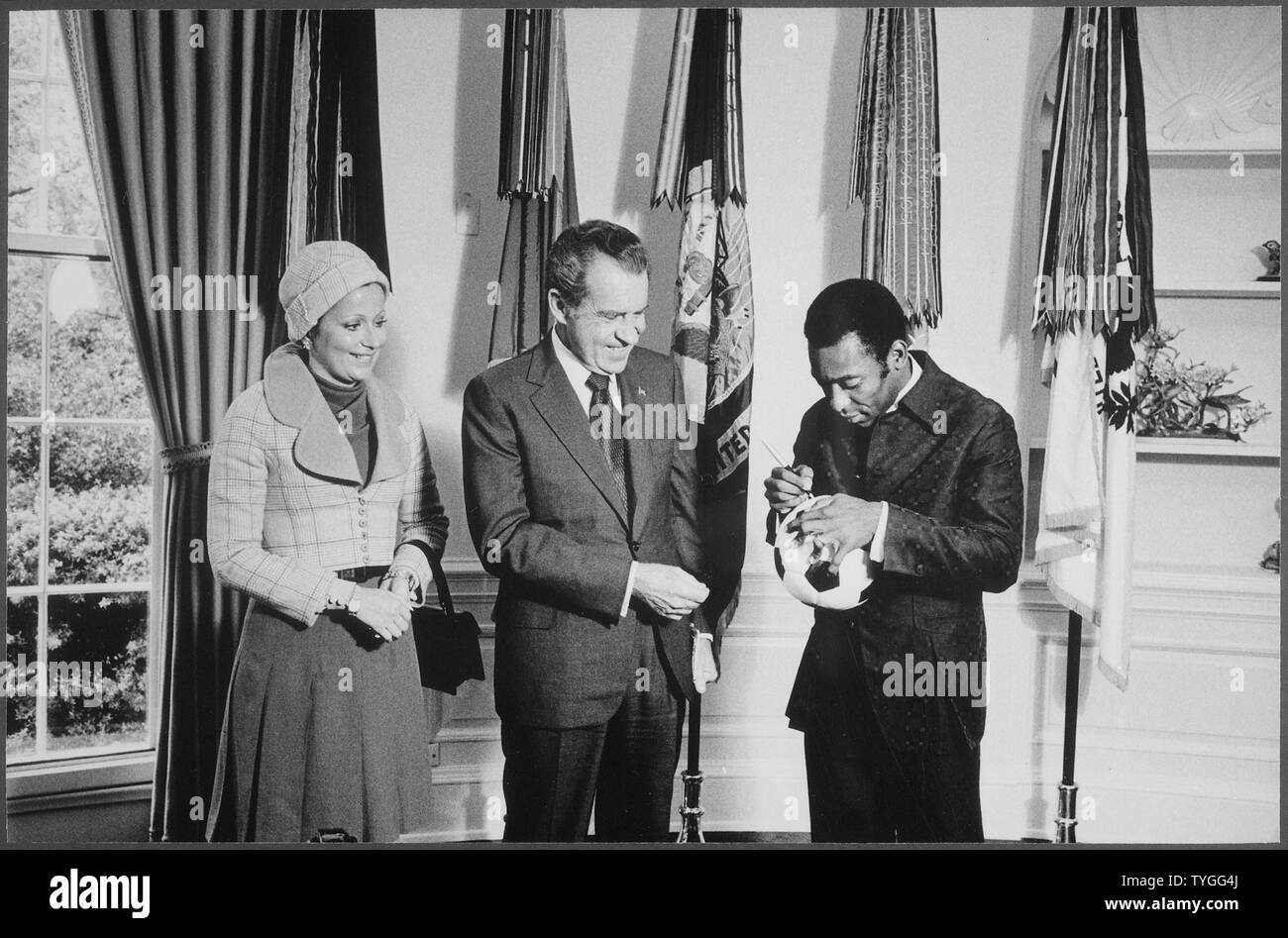 Il presidente Nixon incontro con Edson Pelé Arantes do Nacimento, pensionato brasiliano professionali giocatore di calcio e direttore del calcio internazionale programma sponsorizzato da PepsiCo. Pele autografi di un pallone da calcio per il presidente Nixon, campo di applicazione e il contenuto: nell'immagine: Sig.ra Edson Arantes do Nacimento, Presidente Richard M. Nixon, Edson Pelé Arantes do Nacimento, pensionato brasiliano giocatore di calcio. Oggetto: Sport. Foto Stock