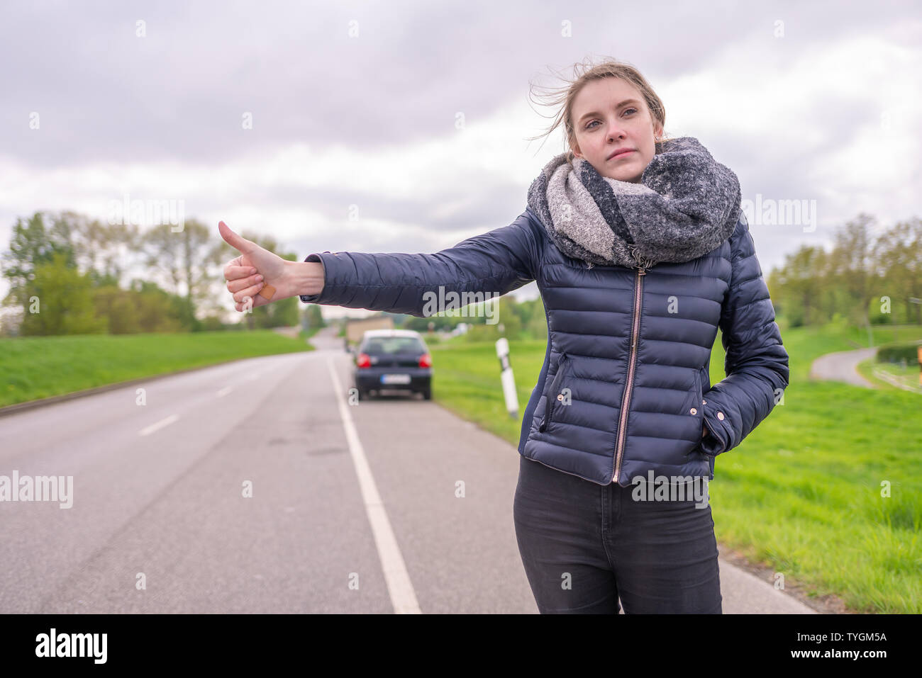 Giovane donna con una ripartizione per auto vuole autostop Foto Stock