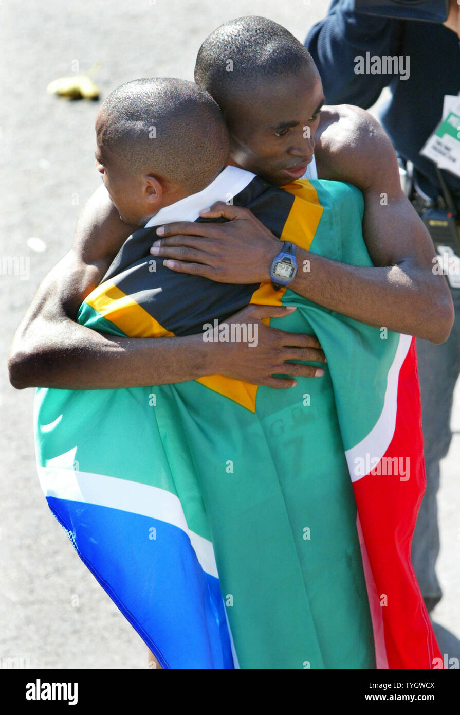 Ramaala Hedrik sinistra, del Sud Africa, indossa il suo paese a bandiera come egli è abbracciato dal secondo posto vincitore Meb Keflezighi degli USA al traguardo della trentacinquesima New York City Marathon con un tempo di 2:09:28 Novembre 7, 2004 a New York City. Oltre 30.000 corridori partecipano in città-ampia la cui gara è nel suo trentacinquesimo anno. (UPI foto/Monika Graff) Foto Stock