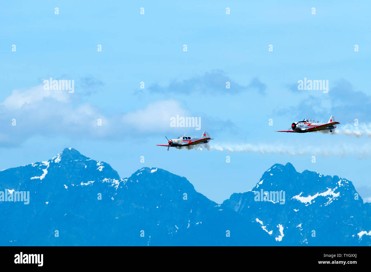 Due aerei acrobatici volando sopra la cima di una montagna durante un'esibizione aerea in Pitt Prati, British Columbia, Canada Foto Stock