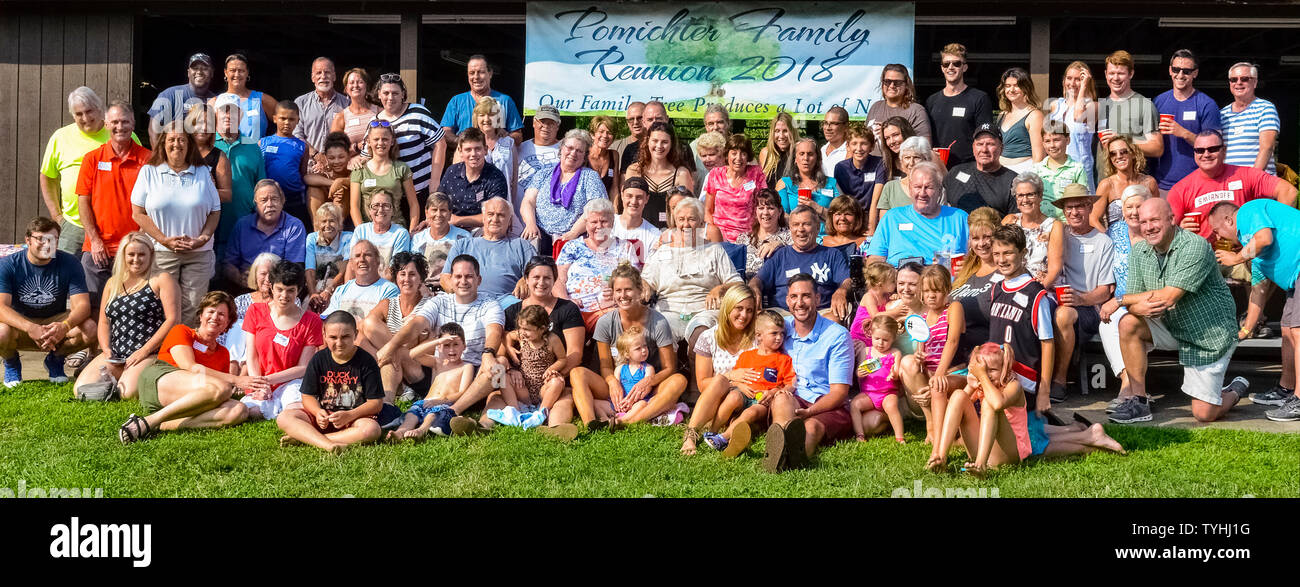 Adulti e bambini di molti secoli posano per una foto di gruppo durante un grande American Family Reunion su una soleggiata giornata estiva nel Connecticut, Stati Uniti d'America. I partecipanti più anziani ad una tipica famiglia reunion sono generalmente i nonni, genitori, fratelli e cugini prima, mentre i più giovani potrebbe essere la seconda, la terza o la quarta cugini. Alcune riunioni familiari sono tenuti su una normale base annuale, o possono essere le occasioni speciali ogni quinto o decimo anno o così. È sempre un tempo di incontrare i membri più recenti della famiglia estesa e di condividere storie, fotografie e cibo. Foto Stock