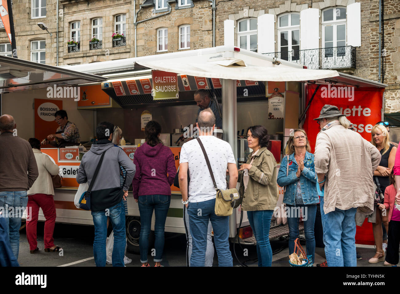 La gente in coda per la galette saucisse (salsiccia alla brace avvolto in crêpe) nel Giovedì Mercato settimanale a Dinan, Bretagna Francia Foto Stock