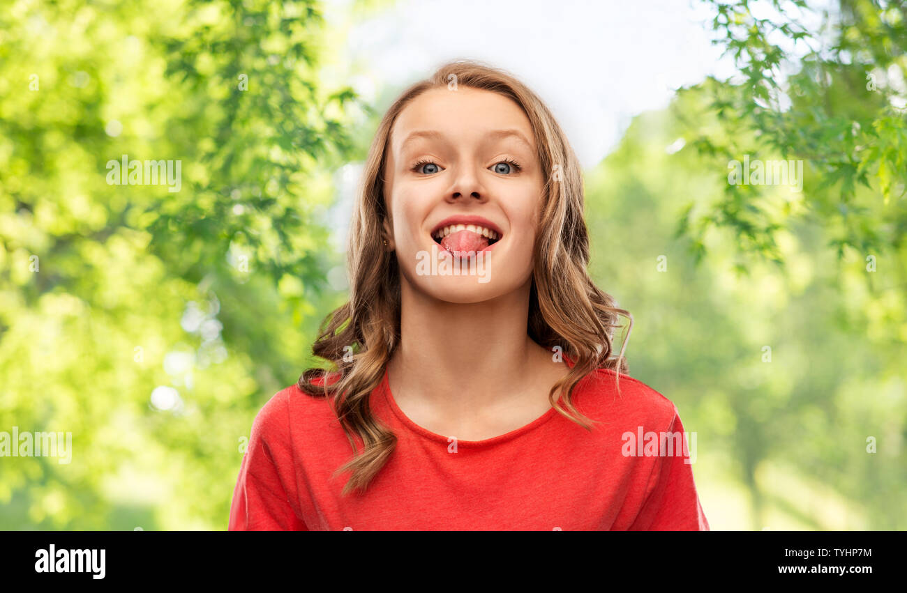 Funny ragazza adolescente in t-shirt rossa che mostra la linguetta Foto Stock