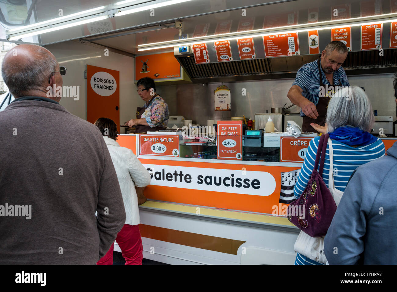 La gente in coda per la galette saucisse (salsiccia alla brace avvolto in crêpe) nel Giovedì Mercato settimanale a Dinan, Bretagna Francia Foto Stock