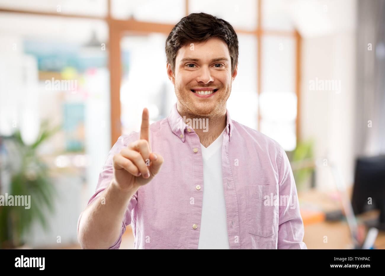 Giovane uomo che mostra un dito sopra office room Foto Stock