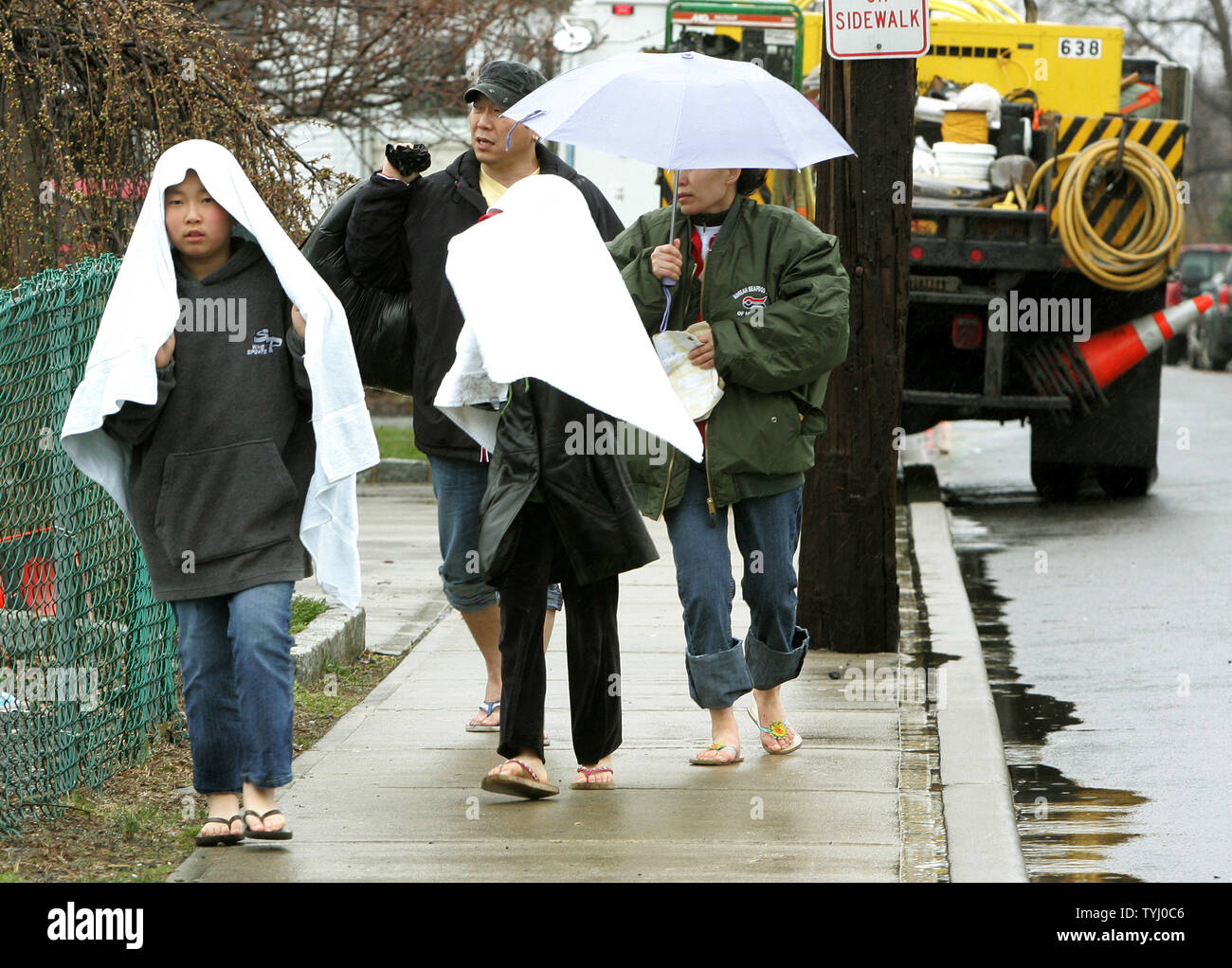 La famiglia Kang a piedi verso il basso il Madison Street dopo aver a lasciare la loro casa allagata come uno stato di emergenza è in effetto dopo una tempesta del nordest a sinistra quantità record di piogge e inondazioni su Aprile 16, 2007 in Mamaroneck, New York. La molla storm caduta oltre sette pollici di pioggia causando interruzioni di alimentazione, street allagamento, chiusure della scuola e la cancellazione di centinaia di voli attraverso la zona. (UPI foto/Monika Graff) Foto Stock