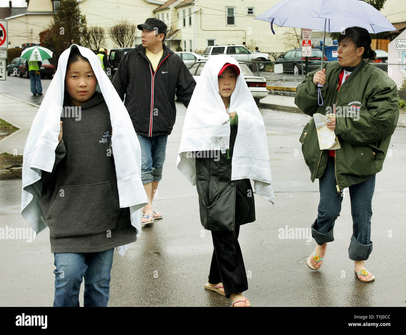 La famiglia Kang a piedi verso il basso il Madison Street dopo aver lasciato la loro casa allagata come uno stato di emergenza è in effetto dopo una tempesta del nordest a sinistra quantità record di piogge e inondazioni su Aprile 16, 2007 in Mamaroneck, New York. La molla storm caduta oltre sette pollici di pioggia causando interruzioni di alimentazione, street allagamento, chiusure della scuola e la cancellazione di centinaia di voli attraverso la zona. (UPI foto/Monika Graff) Foto Stock
