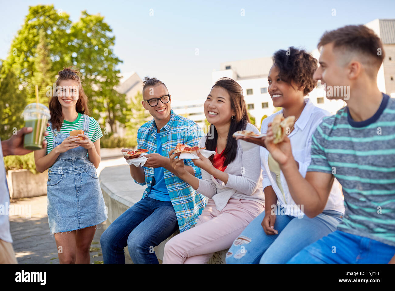 Amici mangiando panini o hamburger in posizione di parcheggio Foto Stock
