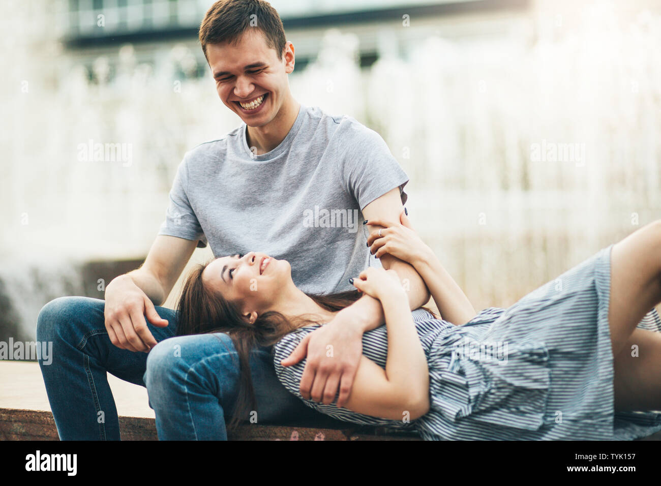 Felice coppia giovane in amore adolescenti amici vestiti in stile casual  seduti insieme vicino a fontana sulla strada di città Foto stock - Alamy
