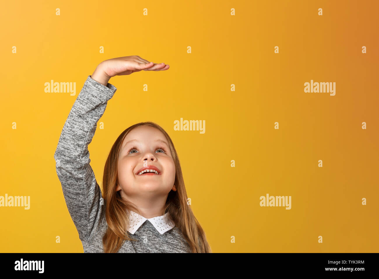 Closeup ritratto di una bambina su uno sfondo giallo. Le misure del bambino la sua altezza. Foto Stock