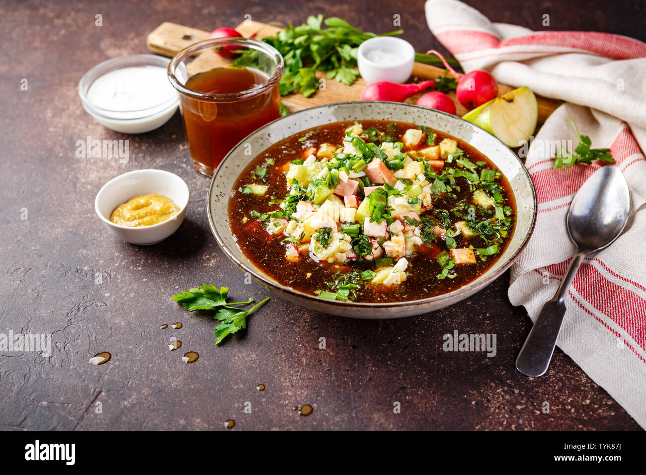 Freddo zuppa russa Okroshka con salsiccia, verdure e kvass nella ciotola e materie prime sul tavolo scuro Foto Stock