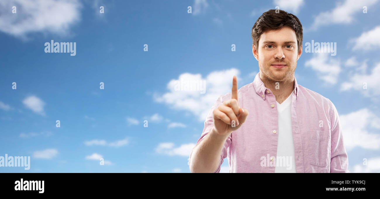 Giovane uomo che mostra un dito sopra il cielo Foto Stock