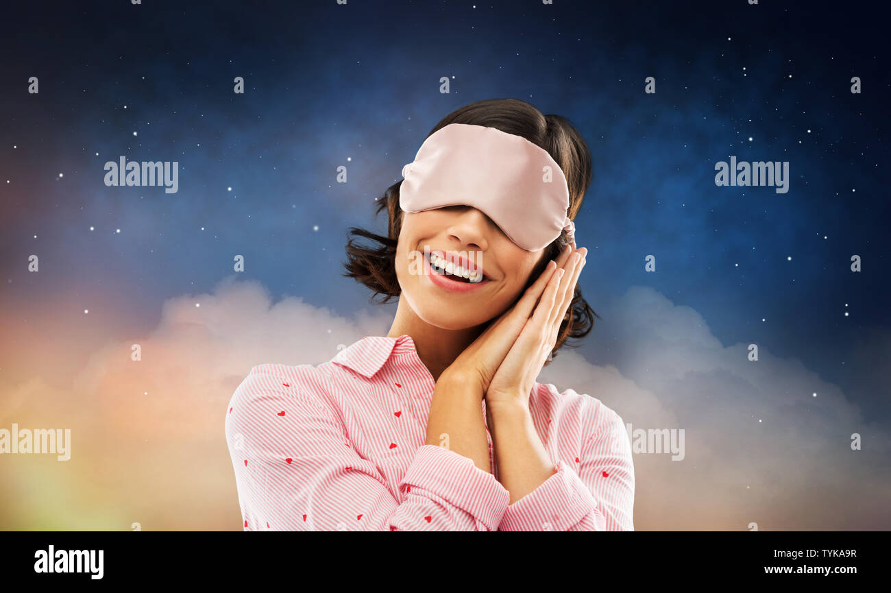 Felice giovane donna in pigiama e occhio maschera del sonno Foto Stock
