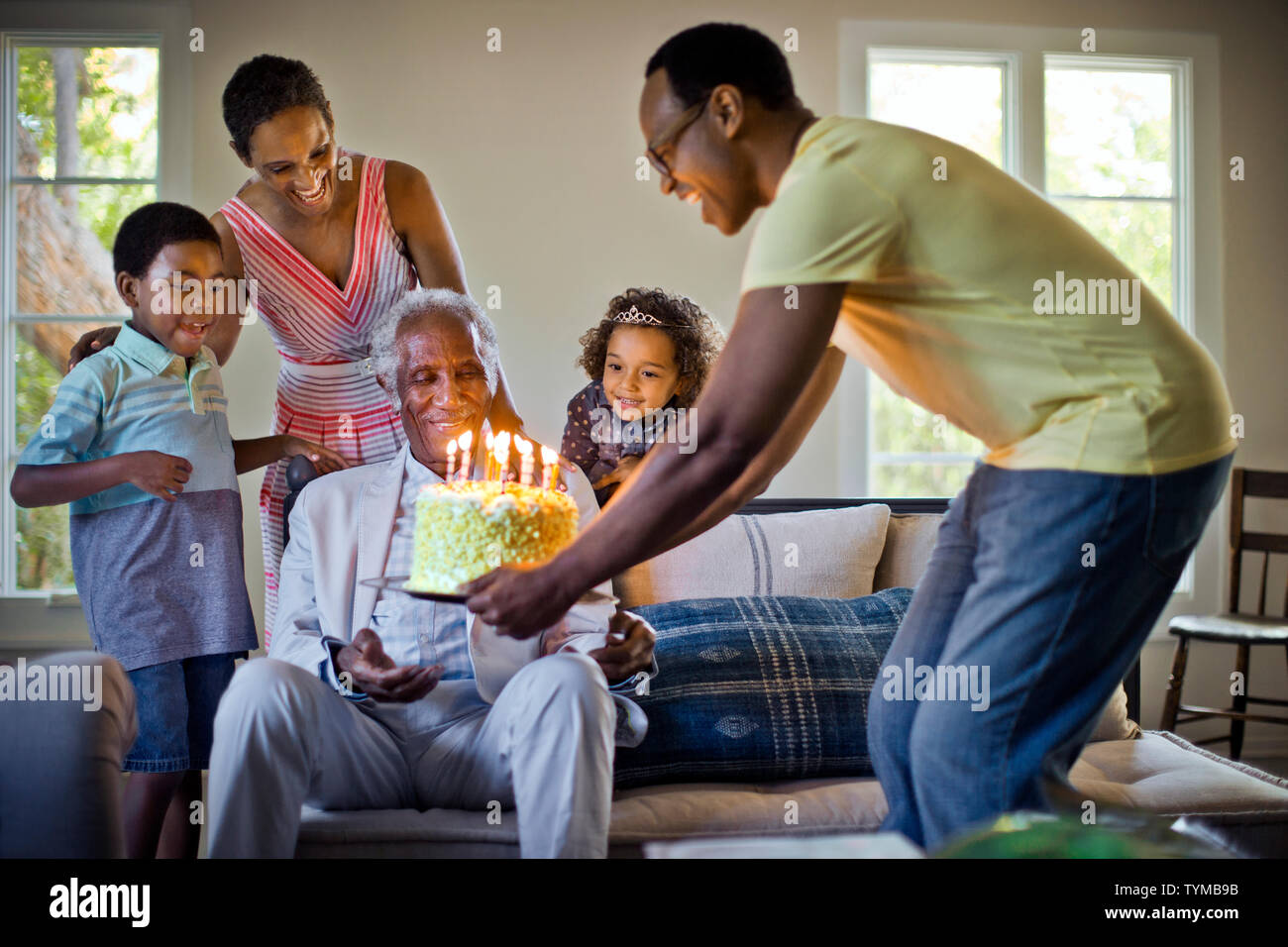 Senior dell'uomo sorprendente la famiglia di lui con una torta per il suo compleanno. Foto Stock