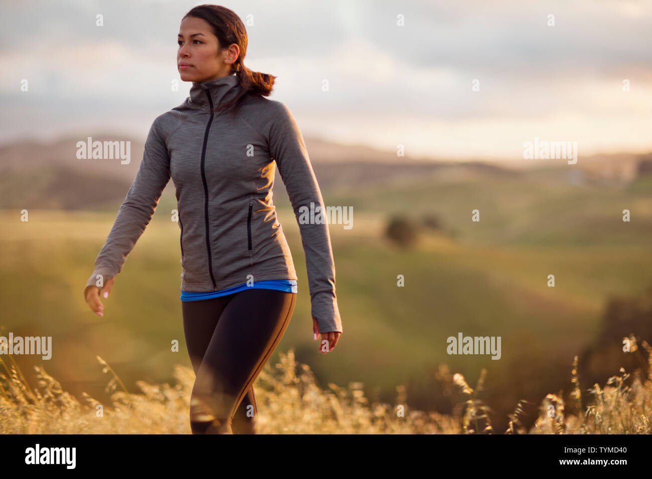 Energico giovane donna a piedi attraverso il paesaggio rurale al tramonto. Foto Stock