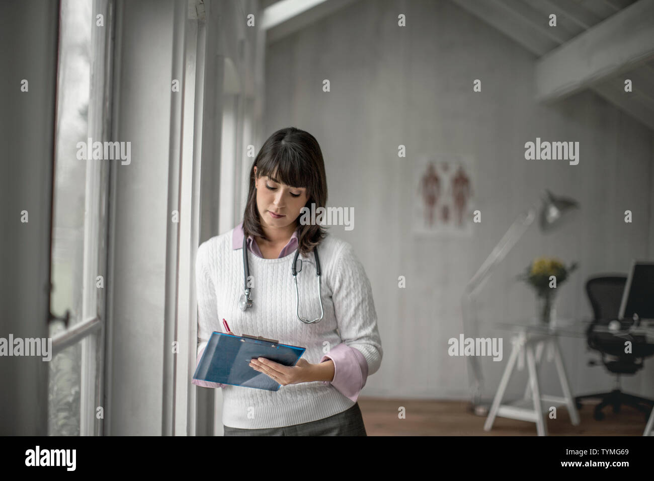 Medico la scrittura su un file nel suo ufficio. Foto Stock