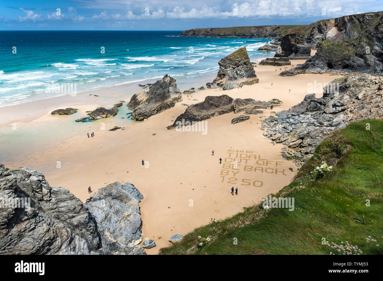 Un messaggio di avvertimento scritto nella sabbia sulla spiaggia di robusta e spettacolare Bedruthan Steps sulla North Cornwall Coast. Foto Stock