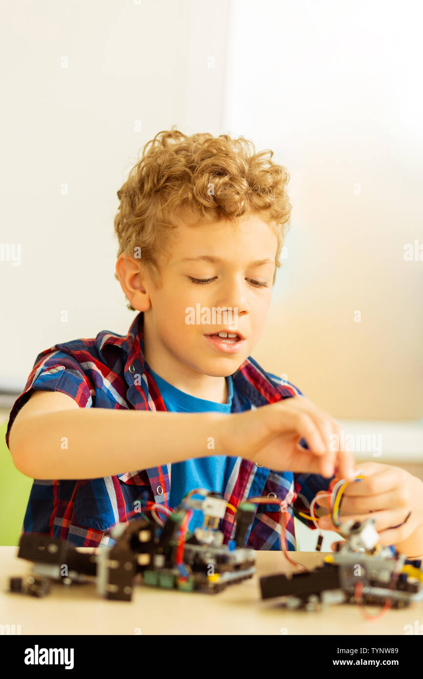 Esperti bambino. Smart ragazzo intelligente di costruire un robot mentre di sviluppare le sue abilità tecniche Foto Stock