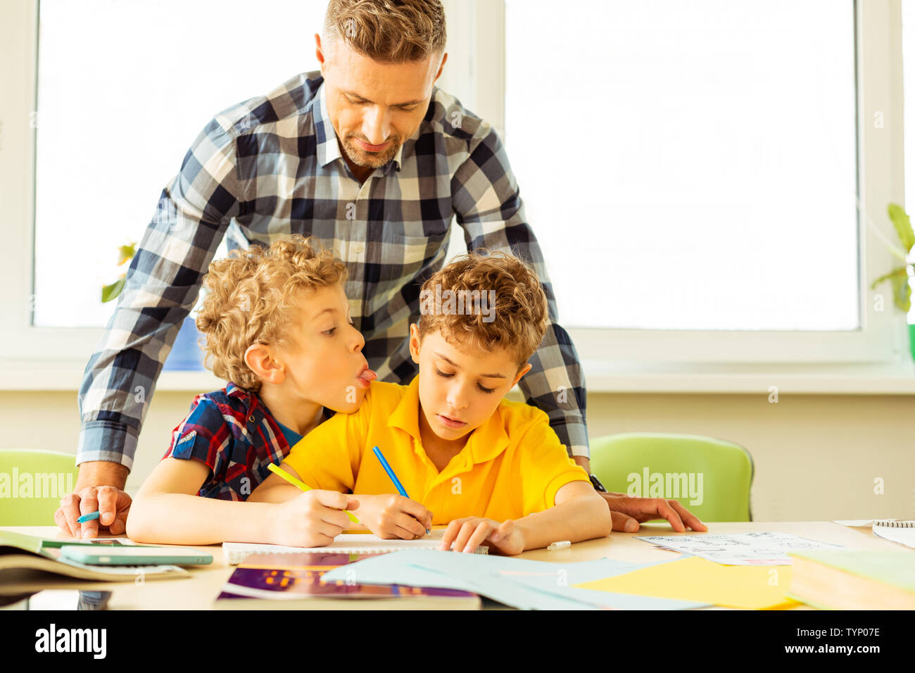 Bad Behavior. Bel ragazzo biondo che mostra la sua lingua mentre teasing suo compagno durante la lezione Foto Stock