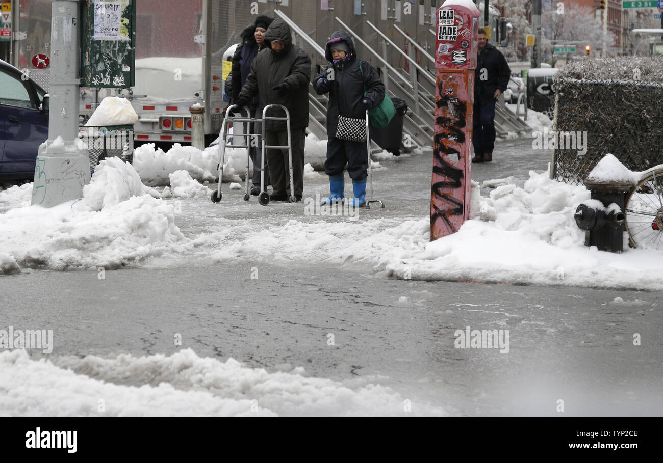 Due persone anziane con scuotipaglia fermare ad un incrocio e guardare un diluvio di ghiaccio e granita su un primo Avenue angolo di strada nell'East Village di New York City il 5 febbraio 2014. Una tempesta di neve che il dumping in presenza di neve e ghiaccio in tutta la zona di triplo stato causarono havoc mercoledì mattina per pendolari e i pedoni. UPI/John Angelillo Foto Stock