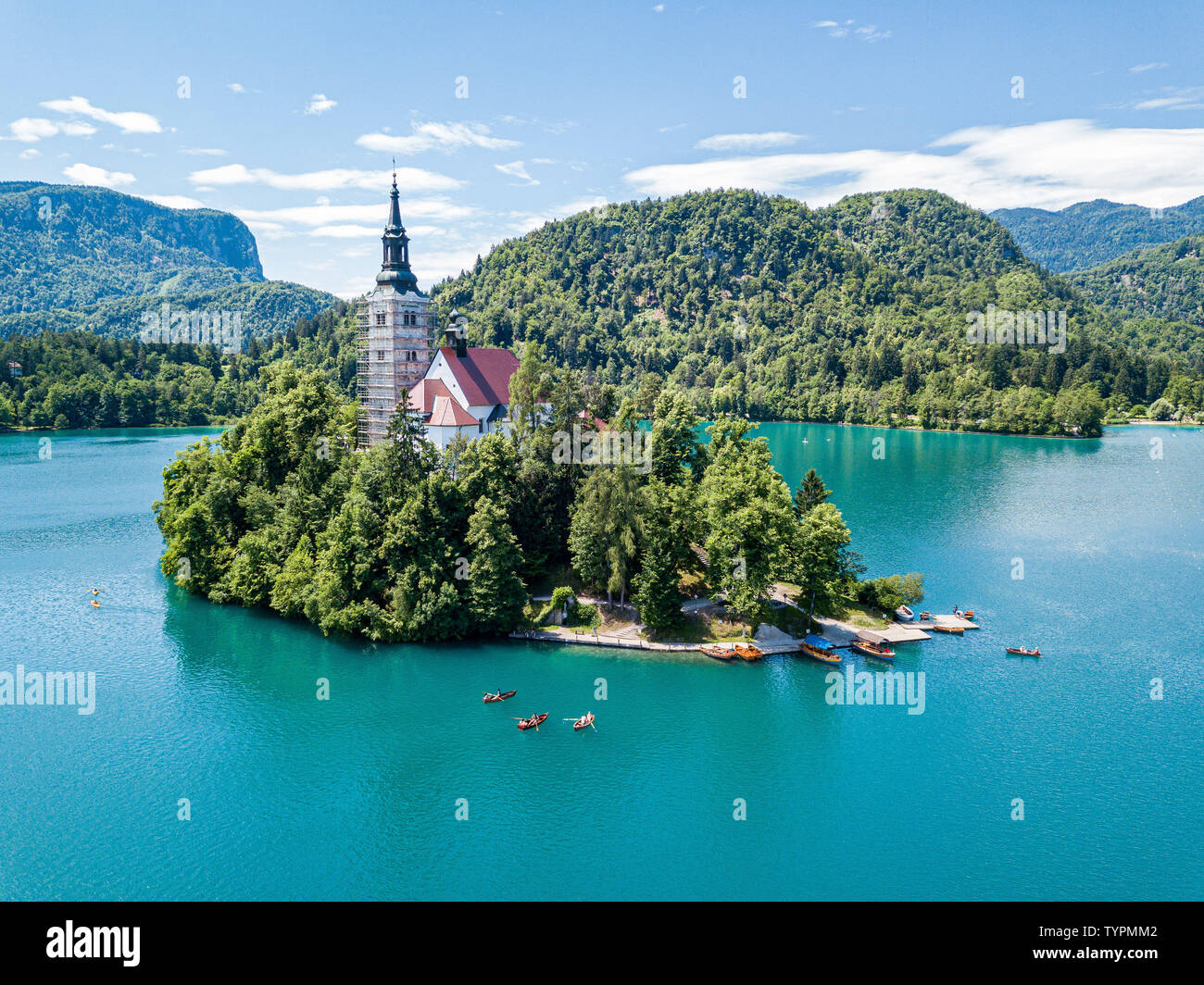 Vista aerea di Bled Island o Blejski Otok, Assunzione di Maria la Chiesa con una torre e la guglia, su mountain bike Lago di Bled pieno di barche pletna, circondato b Foto Stock