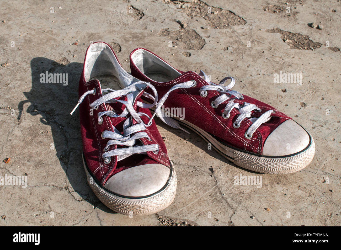 Coppia di usurati rosso vintage vecchia tela sneakers su fuori di superficie di calcestruzzo Foto Stock