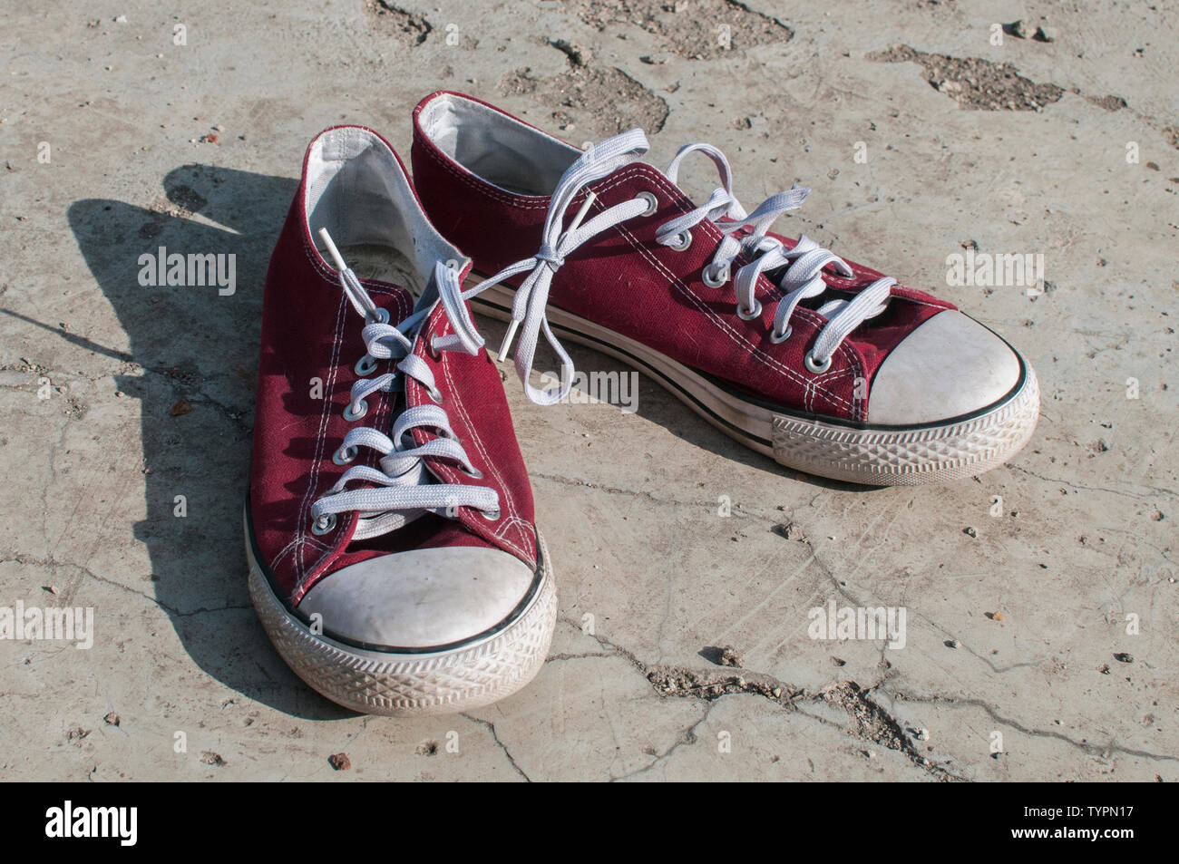 Coppia di usurati rosso vintage vecchia tela sneakers su fuori di superficie di calcestruzzo Foto Stock