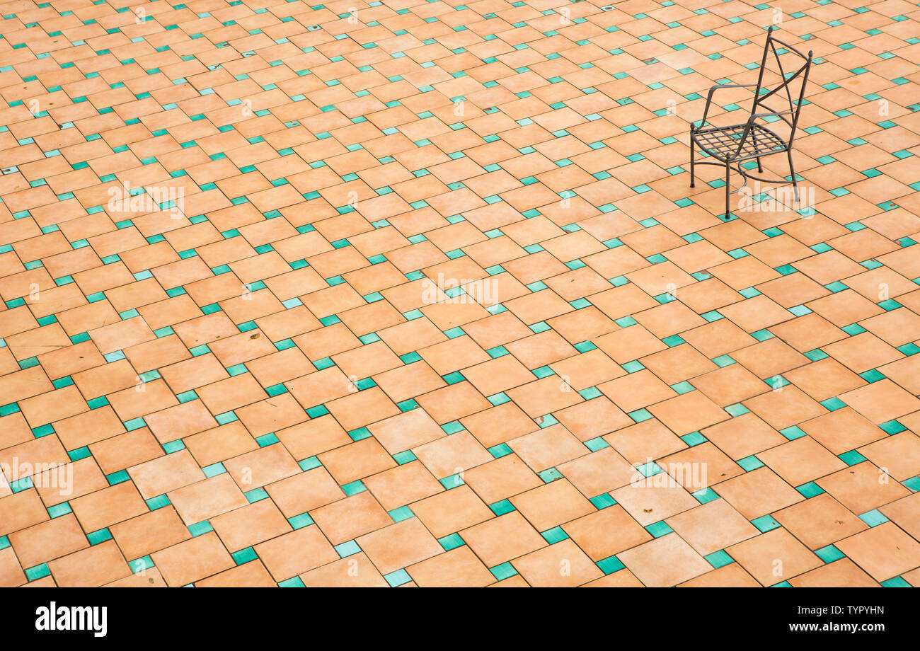 Il ferro solido sedia su una piazza mediterranea lastricata italiana con piastrelle di terracotta Foto Stock