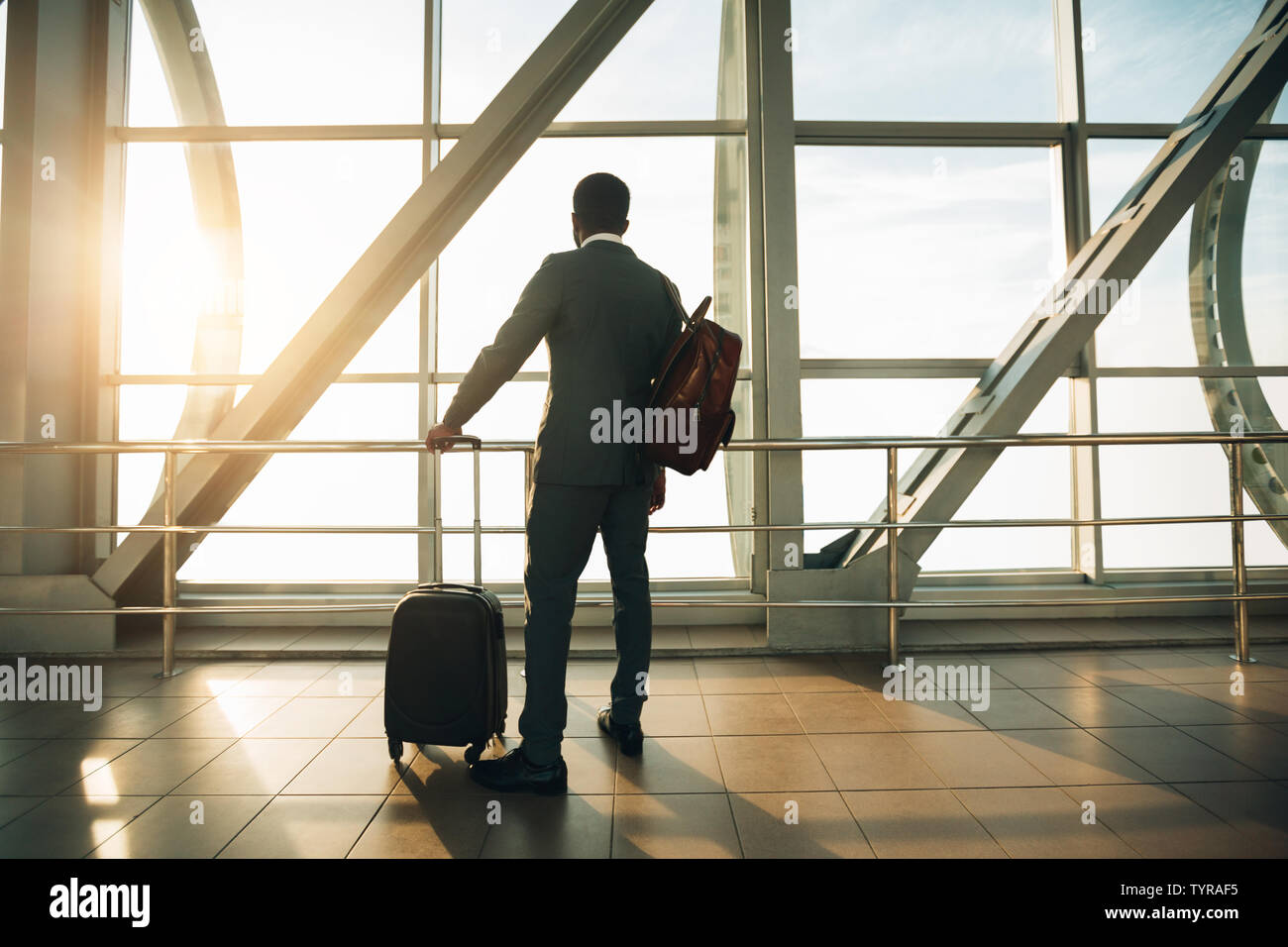 Imprenditore all'Aeroporto terminale gate di imbarco guardando attraverso la finestra Foto Stock