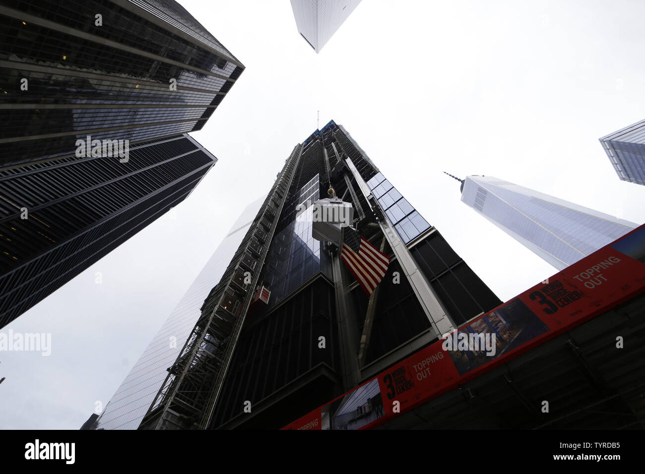 L'ultimo secchio di cemento con una bandiera americana è sollevata in aria con una vista di One World Trade Center presso il topping fuori cerimonia del 3 World Trade Center grattacielo a New York City il 23 giugno 2016. World Trade Center sviluppatore Larry A. Silverstein era unita da più di 500 unione lavoratori edili, così come una moltitudine di funzionari pubblici, i dirigenti aziendali e i rappresentanti della comunità locale per celebrare il topping fuori 3 World Trade Center. L'ultimo secchio di calcestruzzo per la 80-storia grattacielo sarà firmato da Larry Silverstein e altri dignitari e sollevato 1.079 a pagamento Foto Stock