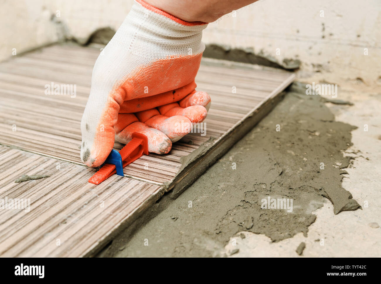 Installatore la mano è utilizzando cunei in plastica ed i fermi di allineamento per piastrelle insieme. Foto Stock