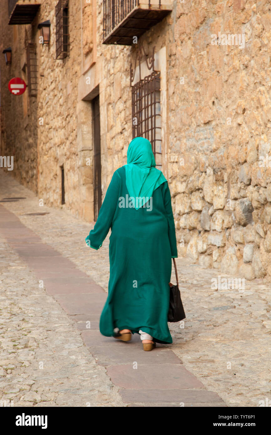 Donna musulmana tradizionalmente vestita a piedi attraverso la città medievale murata moresca di Albarracin Spagna Foto Stock