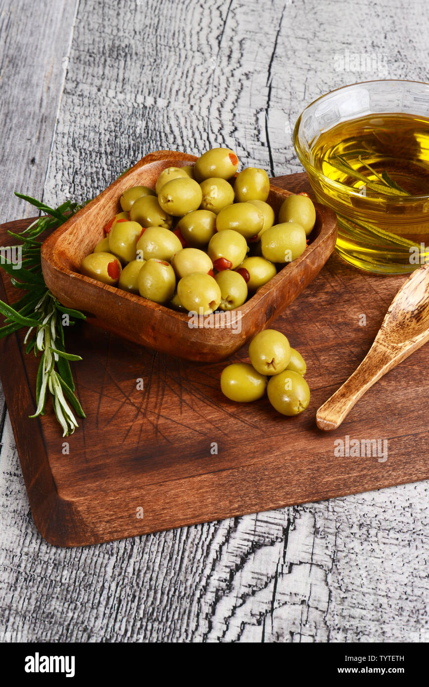 Ciotola di legno di pimento olive con erbe di rosmarino Foto Stock