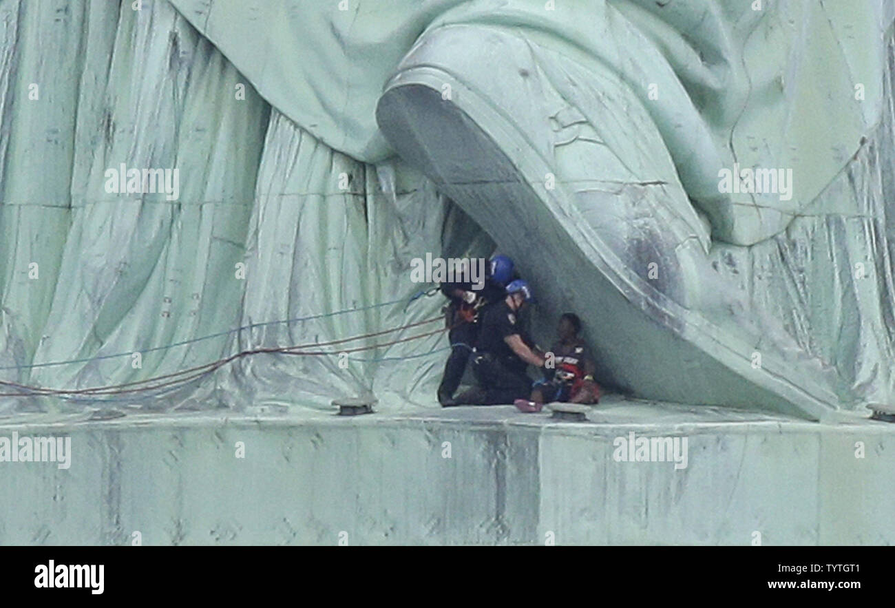 Affrontare la polizia e scorta di una donna che sono saliti alla base del retro della Statua della Libertà in giù verso massa sul Giorno Di Indipendenza a New York City il 4 luglio 2018 in New York City. Una donna parzialmente risalito fino alla Statua della Libertà mercoledì spingendo le autorità ad evacuare Liberty Island. Almeno sei manifestanti sono stati arrestati al monumento nella prima giornata dopo aver appeso un banner dal piedistallo blasonate con un messaggio circa la soppressione di ghiaccio, immigrazione degli Stati Uniti agenzia di esecuzione. Foto di Giovanni Angelillo/UPI Foto Stock