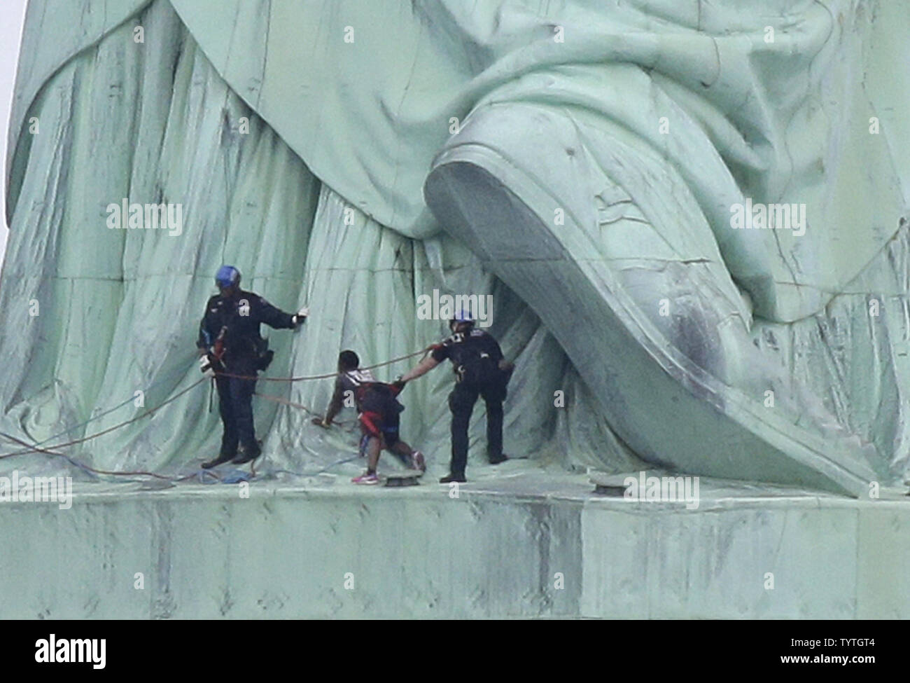 Affrontare la polizia e scorta di una donna che sono saliti alla base del retro della Statua della Libertà in giù verso massa sul Giorno Di Indipendenza a New York City il 4 luglio 2018 in New York City. Una donna parzialmente risalito fino alla Statua della Libertà mercoledì spingendo le autorità ad evacuare Liberty Island. Almeno sei manifestanti sono stati arrestati al monumento nella prima giornata dopo aver appeso un banner dal piedistallo blasonate con un messaggio circa la soppressione di ghiaccio, immigrazione degli Stati Uniti agenzia di esecuzione. Foto di Giovanni Angelillo/UPI Foto Stock