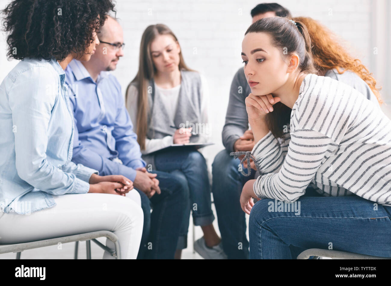 Sottolineato premurosa donna durante il gruppo di terapia di riabilitazione Foto Stock