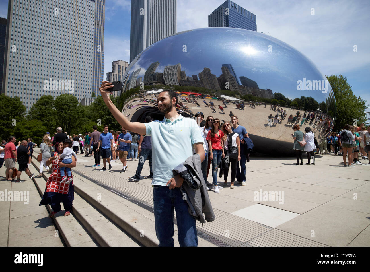 I visitatori e i turisti per il Millennium Park in una trafficata sabato mattina in estate prendere foto e selfies vicino al cloud gate bean scultura in Chicago IO Foto Stock