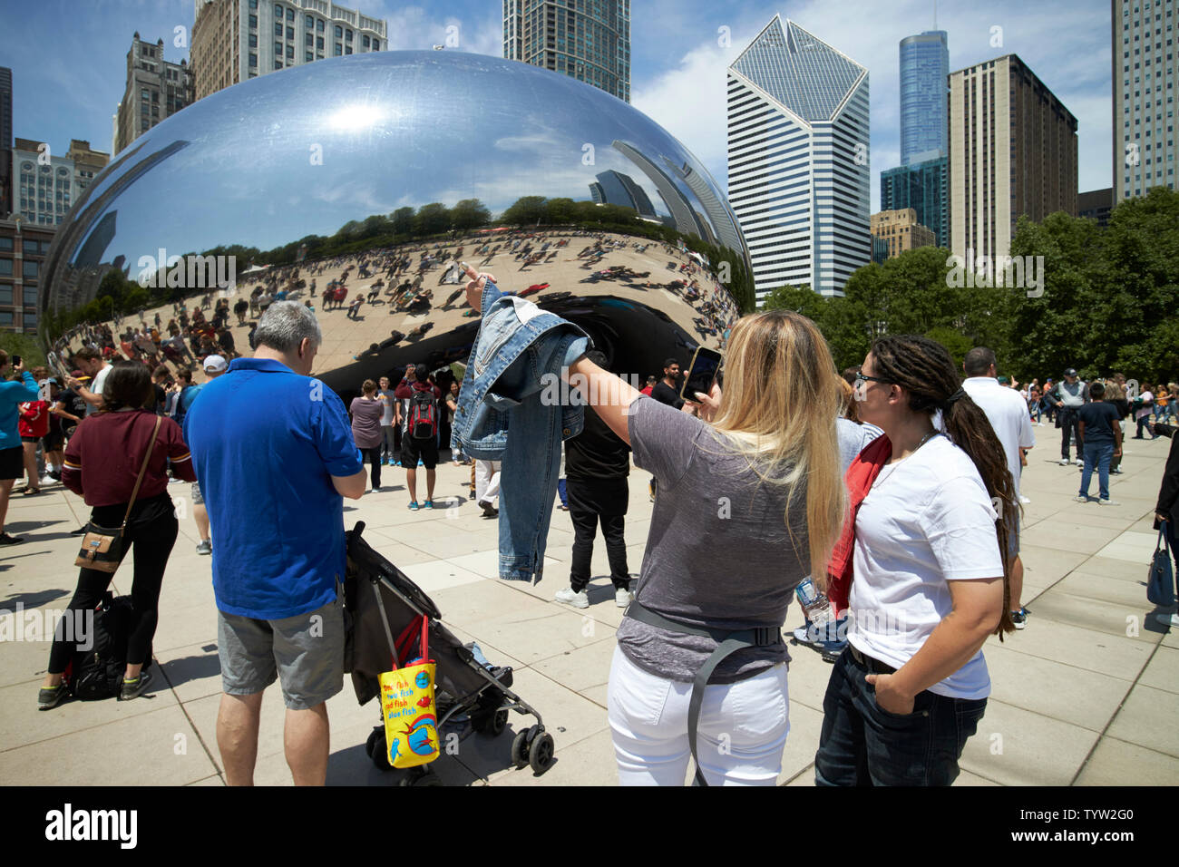I visitatori e i turisti per il Millennium Park in una trafficata sabato mattina in estate prendere foto e selfies vicino al cloud gate bean scultura in Chicago IO Foto Stock