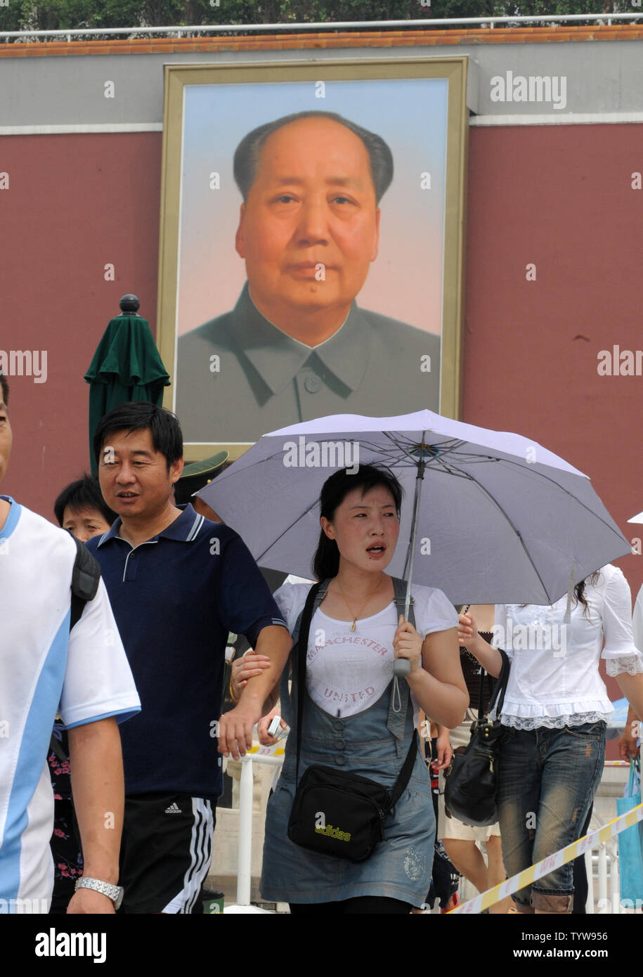 Una donna cinese detiene un ombrello per la stessa protezione dal sole e il calore come lei lascia la Città Proibita di fronte del ritratto dell ex Presidente Mao Zedong a Pechino il 4 agosto 2008. Cinesi e stranieri Olympic i visitatori accorsi a zone turistiche vicino alla Città Proibita, la quale è adiacente alla piazza Tiananmen prima dell'inizio dei Giochi Olimpici Estivi on August 8th. (UPI foto/Pat Benic) Foto Stock