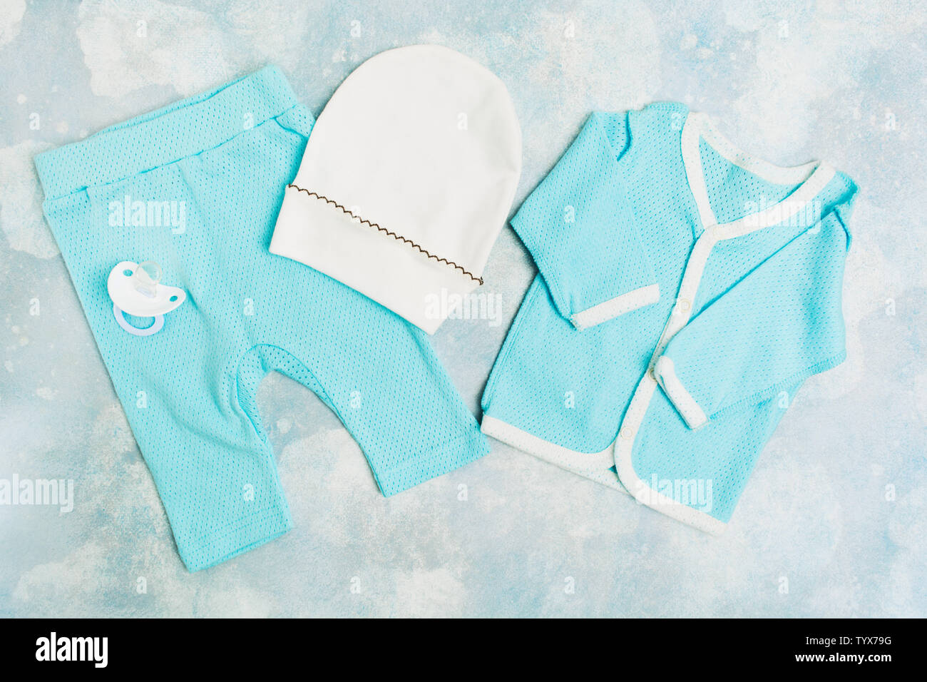 Blue Baby Suit con cappello bianco e il succhietto in silicone testurizzata su sfondo blu. Baby nightshirt alla moda. Lay piatto Foto Stock