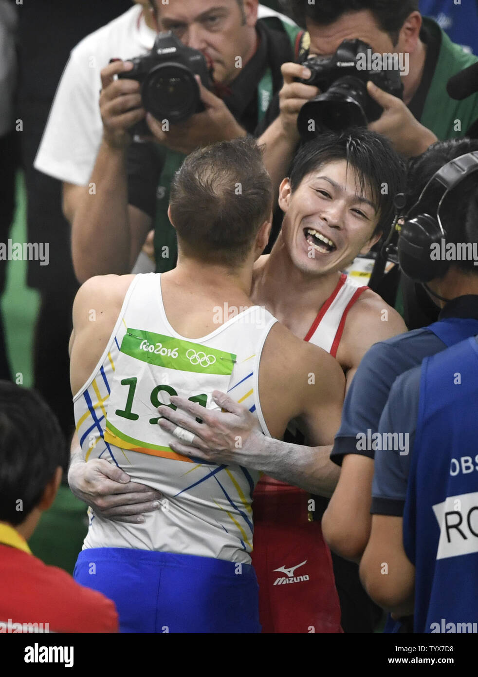 Ginnasta giapponese Kohei Uchimura (R), in giubilo per vincere la medaglia d'oro abbracci dell'Ucraina Oleg Verniaiev, che ha vinto l'argento, a conclusione dell'uomo di ginnastica artistica completa individuali finali del Rio 2016 Olimpiadi di estate a Rio de Janeiro, Brasile, 10 agosto 2016. Gran Bretagna Max Whitlock ha vinto la medaglia di bronzo. Foto di Mike Theiler/UPI Foto Stock