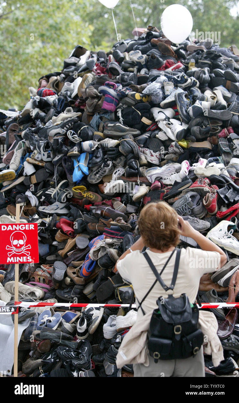 Una donna prende le fotografie di un "pyramide di scarpe' di Parigi, sabato 30 settembre, 2006. Residenti impilate le loro vecchie scarpe in solidarietà con Handicap International il tentativo di portare l attenzione per esigenze di un divieto globale delle mine antiuomo e le bombe a grappolo. (UPI foto/Eco Clemente) Foto Stock