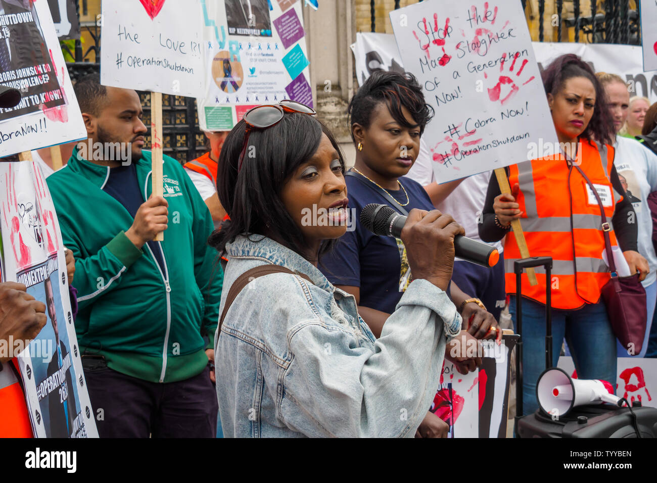 Londra, Regno Unito. Il 26 giugno 2019. Taglierini attivisti di arresto di funzionamento, un consorzio di mamme, papà e vittime di altri membri della famiglia e cari supportato da altri attivisti, chiamato per la comunità a unirsi a lavorare per porre fine alla violenza e ha chiesto una riunione di emergenza del comitato risposta COBRA per avviare azioni urgenti da parte del governo. Alla protesta al di fuori del Parlamento hanno versato sangue finto sulle loro mani e reso handprints sul marciapiede. Peter Marshall / Alamy Live News Foto Stock